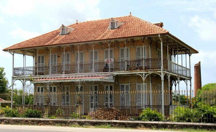 Une maison coloniale typique de Guadeloupe avec sa véranda et ses volets en bois.