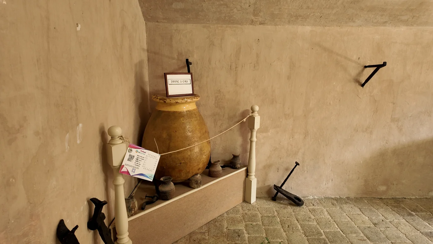 Grande jarre à eau et poteries exposées dans une salle du musée du Fort Napoléon